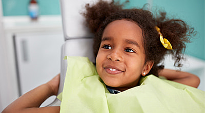 Young child smiling during an infant oral exam at a pediatric dentist in Austin, TX