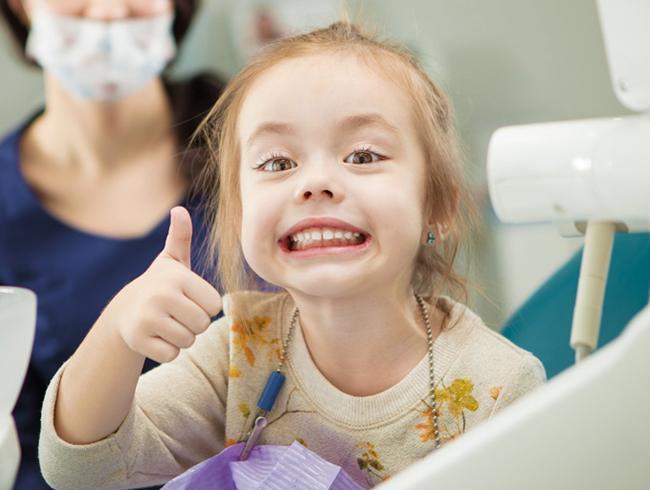 Child smiling after pediatric root canal treatment on baby teeth in Austin, TX