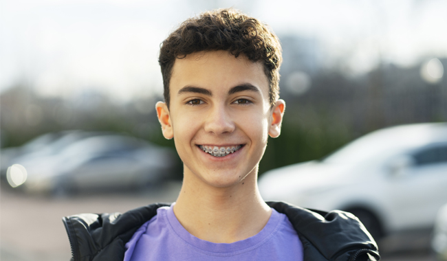 Teen smiling with braces after orthodontic evaluation at Hapii Dental in Austin TX