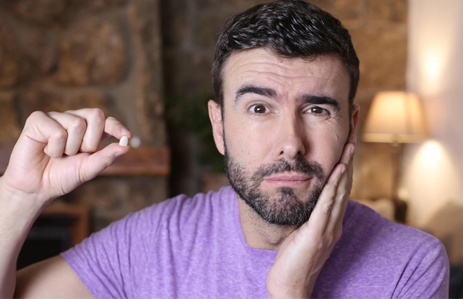 Patient holding an extracted tooth and touching jaw due to tooth pain before extraction treatment in Austin, TX